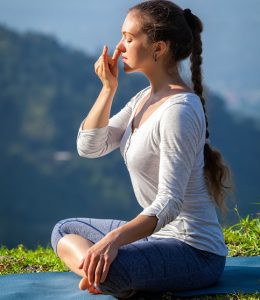 Woman practices pranayama yoga breath control in lotus pose padmasana outdoors in Himalayas in the morning on sunrise. Himachal Pradesh, India